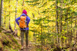 Autumn hike backpacker lifestyle woman walking on trek trail in forest outdoors with yellow leaves foliage. Fall outdoor activity girl with bacpack and cold season gear hiking outside.