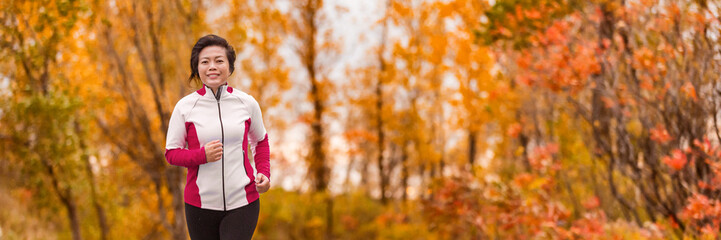 Autumn running middle age Asian woman jogging in park banner panorama. Active lifestyle mature lady in her 50s living a healthy life.