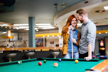 Beautiful couple playing billiards