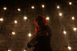 © singulyarra - Girl in glasses poses near wall in black studio with garlands of lamps, under view