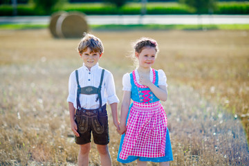 Two kids, boy and girl in traditional Bavarian costumes in wheat field