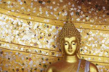 golden buddha statue with gold leaf texture as copyspace background.