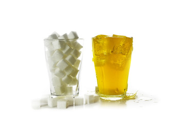 glass full of sugar cubes compared to a glass with a yellow sweet beverage, isolated on a white background