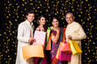 Stock Photo of cheerful indian family with shopping bags in traditional wear in diwali isolated over black background