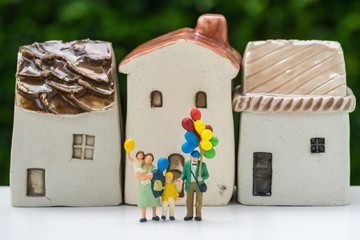 Wall Mural - Miniature happy family holding balloons with ceramic house as property or mortgage concept