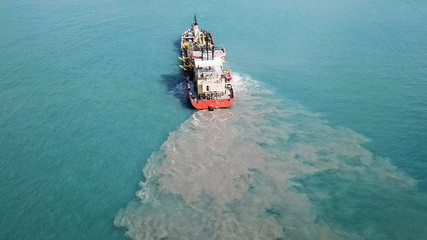 Suction Dredger ship working near the port - with mud, Pollution, brown Muddy water - aerial tip down shot