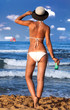 © nikilitov - Young woman in white swimsuit holding glass of cold fresh cocktail sunbathing at sea shore.