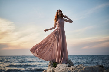 woman in a long pink dress on the beach, sunset