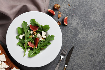 Wall Mural - Seasonal salad with figs, arugula, walnuts and feta cheese on textured stone background