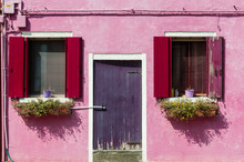 Colorful Windows And Door With Shutters On A Pink Stucco House