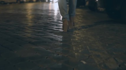 Wall Mural - Close-up view of female feet walking in the evening through the pavement road, light from the cars on the road.