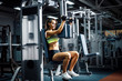 Young and sporty woman using pectoral fly machine in the gym