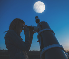 Wall Mural - girl looking at the moon through a telescope.