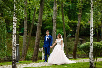 Wall Mural - Bride and groom walking and holding hands in the forest on nature