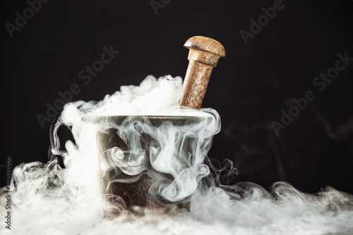 Foto Closeup rusty vintage mortar filled with magic potion and deep smoke around at black background