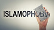 Man's hand erasing the word islamophobia