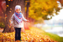Adorable Happy Girl Playing With Fallen Leaves In Autumn Park