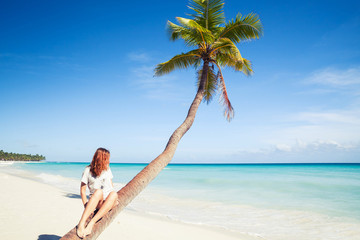 Girl sitting on a palm tree. Saona island beach