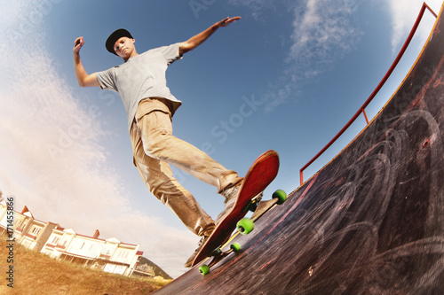 Papel de parede Teen skater hang up over a ramp on a skateboard in a skate park