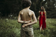 © Cavan Images - Shirtless son holding flowers behind back with mother in background