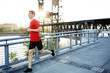 © Cavan Images - Side view of man jogging on bridge against clear sky