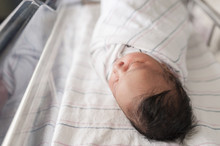 High Angle View Of Sleeping Newborn Baby In Hospital Crib