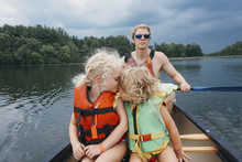 Sister Kissing Girl While Father Canoeing In Lake