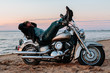 Man sleeping on a motorcycle on the beach at sunset