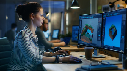 Wall Mural - female game developer works on a level design on her personal computer with two displays. she works 