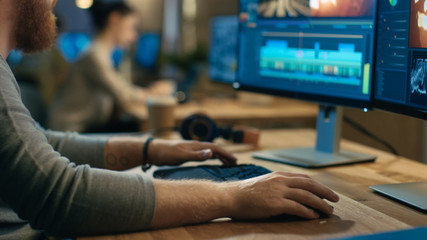 Wall Mural - male videographer edits and cuts footage and sound on his personal computer with two displays. his o
