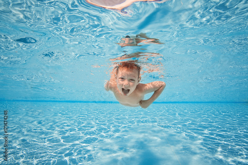 Plakat Szczęśliwy młody chłopak pływać i nurkować pod wodą, pierś dziecko uderzenie z zabawy w basenie. Aktywny zdrowy styl życia, aktywność sportów wodnych i lekcje z rodzicami na letnie rodzinne wakacje z dzieckiem