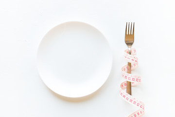 Wall Mural - fork wrapped in a measuring tape and an empty plate on a white background