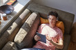 © ALTO IMAGES/Stocksy - Young Man Using Digital Tablet And Headphones While Lying On Sof