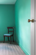© Phillips Visuals/Stocksy - Chair in the corner of a green  room.