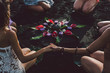 © Nabi Tang/Stocksy - Women on the beach join hands around the flower mandala