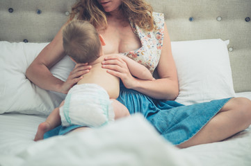 Mother breastfeeding baby in bed