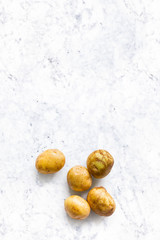 Wall Mural - beautiful small rounded whole organic potato with the peel isolated on white marble kitchen top. Vertical composition. Top view