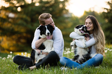 Romantic couple in love walking dogs in nature and smiling