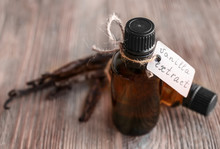 Bottles With Vanilla Extract And  Sticks On Wooden Background