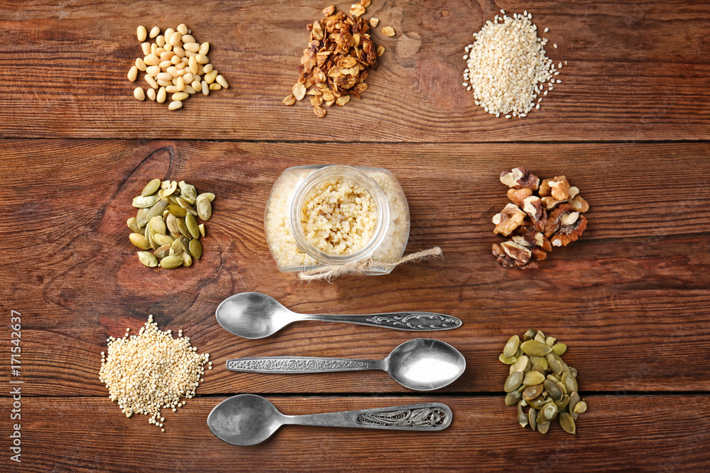 Composition with quinoa, walnuts, pumpkin seeds and granola on wooden background