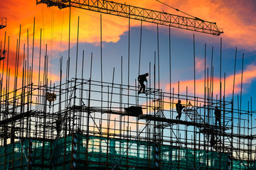 Construction site with crane and workers at sunset