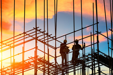 workers and construction site at sunset