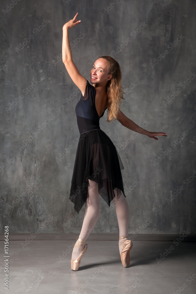 Young beautiful ballet dancer with black hair in a black dress, pointe  shoes smiling and beautifully dancing ballet in a dark dance studio Stock  Photo | Adobe Stock
