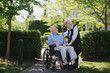 © Rob and Julia Campbell/Stocksy - Tender moment between senior couple outside together with wheelchair