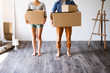 Unrecognizable couple with boxes moving in new house.