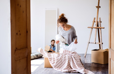 Wall Mural - Young couple moving in new house, unpacking boxes.