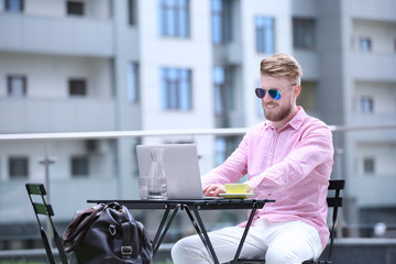 Wall Mural - Young blogger with laptop working at table, outdoors