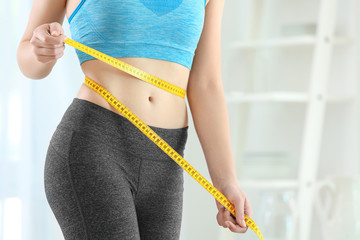 Poster - Young woman with measuring tape at home. Diet concept