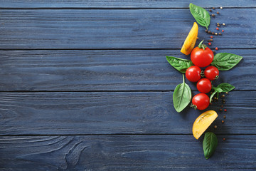 Composition with green fresh organic basil, yellow and red tomatoes on wooden background