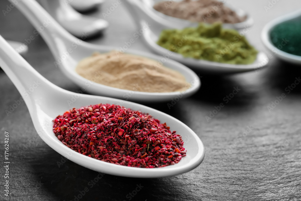 Maqui berry powder in white ceramic spoon on black background